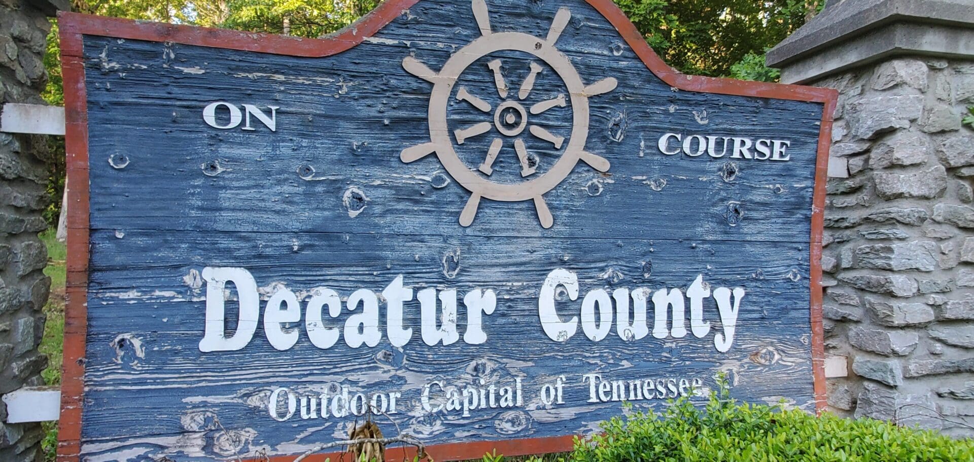 A weathered wooden sign with a ship's wheel and text about Decatur County.