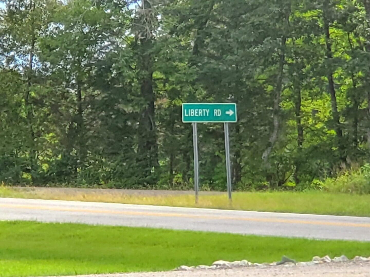 A green road sign indicating Liberty, 40 miles ahead on a rural road.