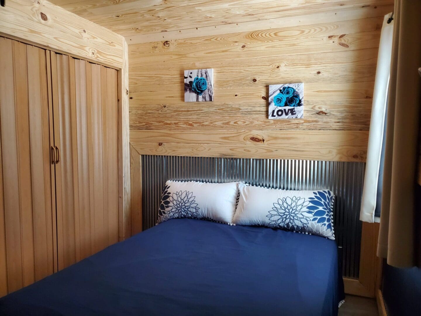 Cozy wooden bedroom with blue bedding and decorative pillows.