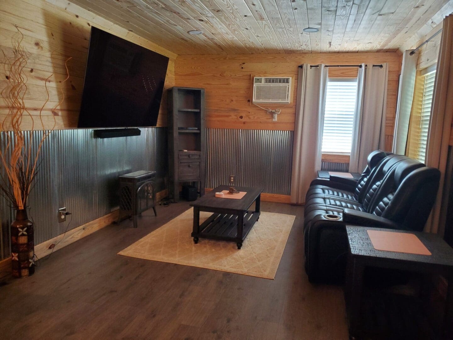 Cozy living room with black leather sofa and wall-mounted TV.