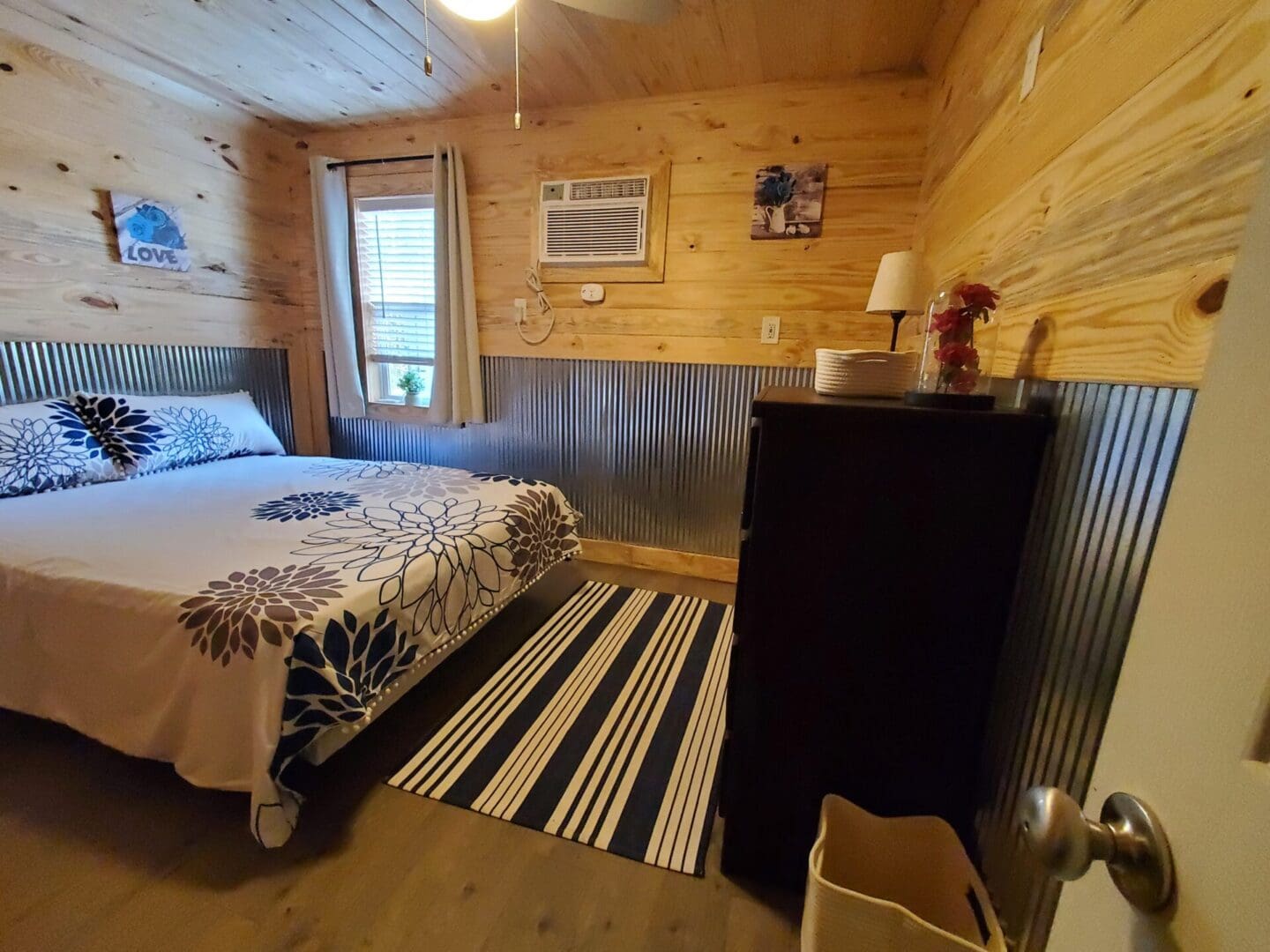 Cozy bedroom with wood panel walls and a black dresser.