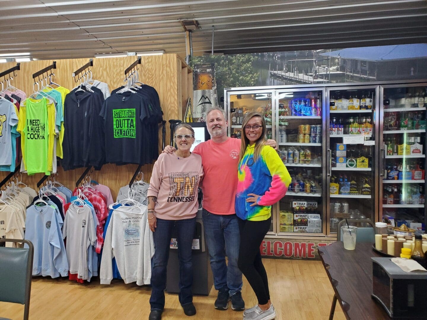 Three people standing in a clothing and goods store.