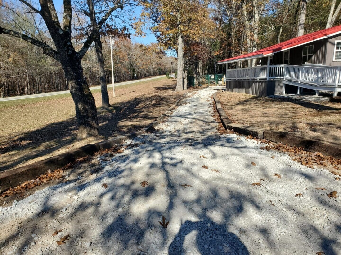 A newly paved concrete path surrounded by trees and a building.