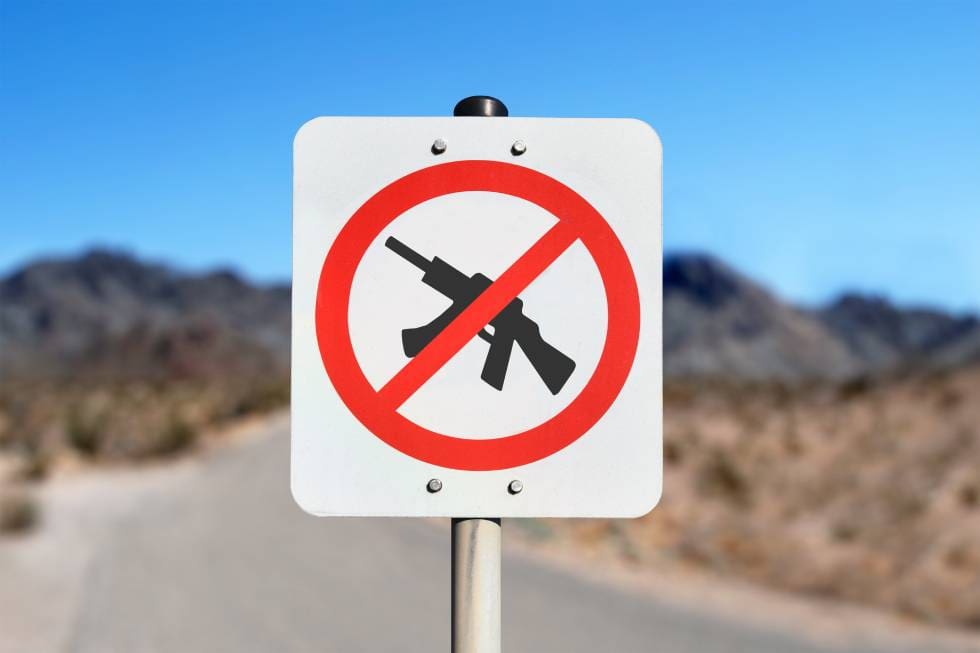 No guns allowed sign on a desert road.