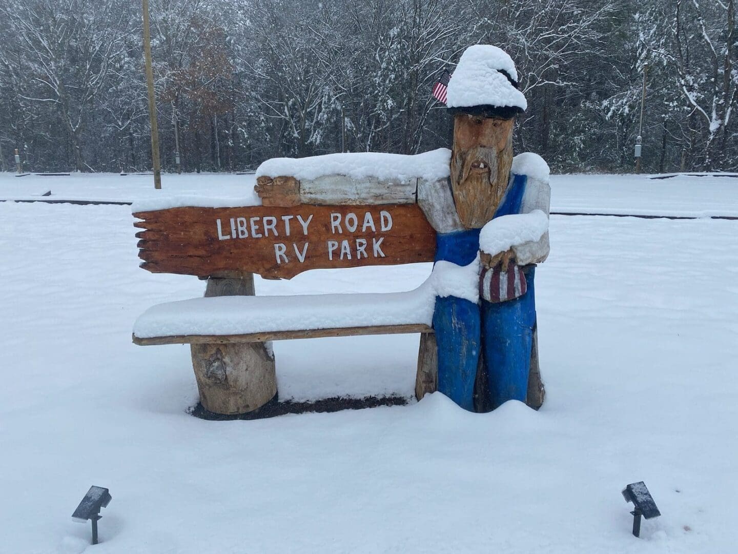 A wooden bench and figure covered in snow at Liberty Road RV Park.
