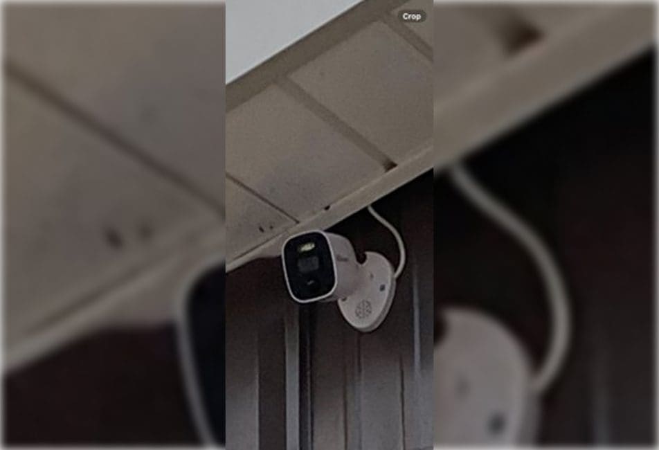 A white security camera mounted under a surface, angled downwards.