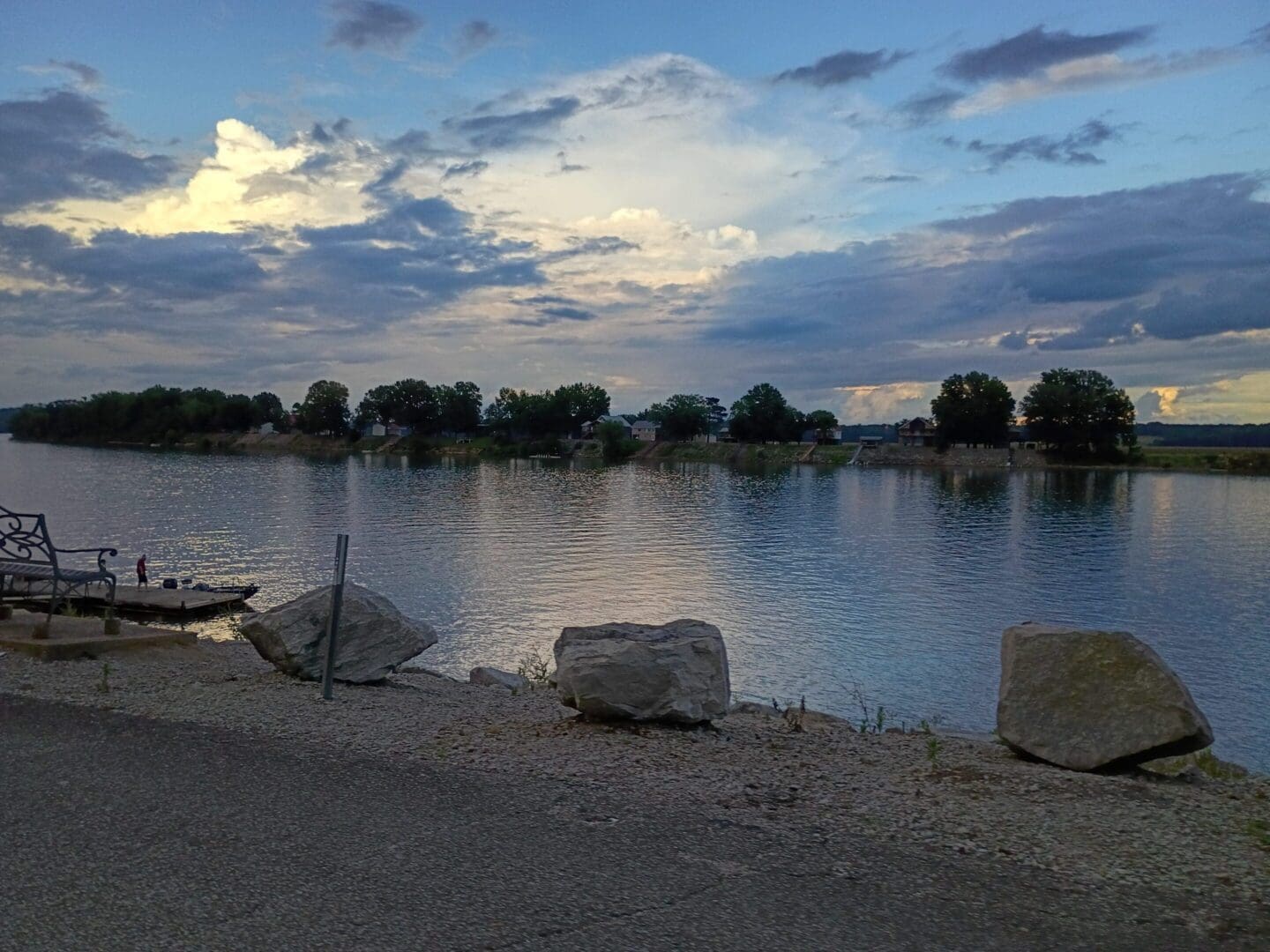 Calm river under cloudy evening sky.