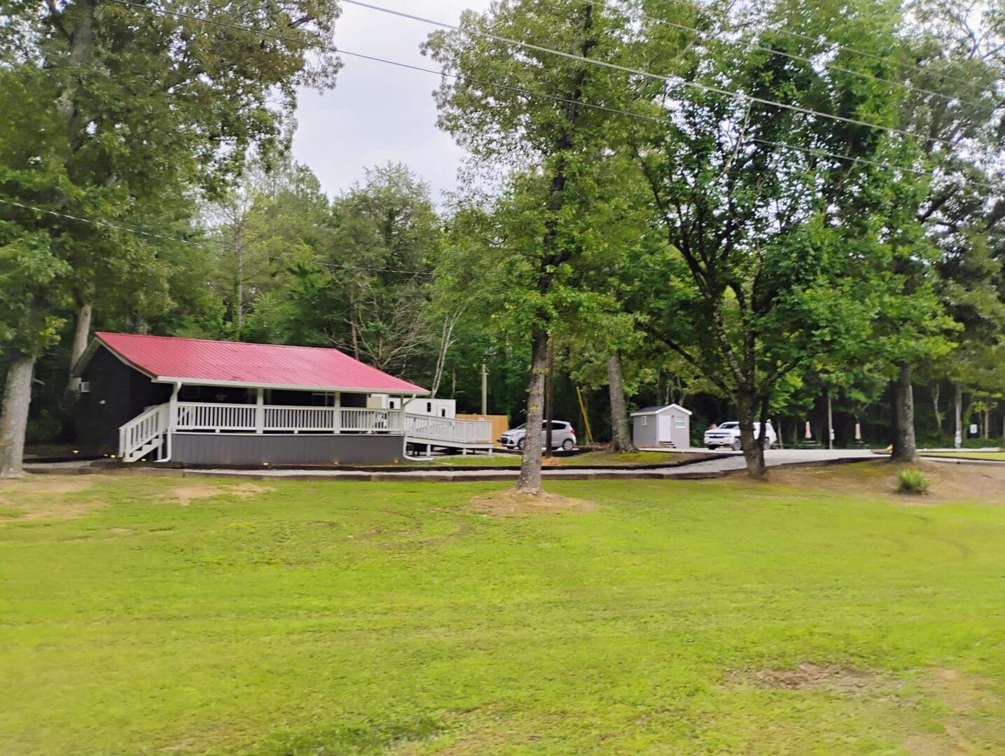 A green park area with large trees and a building with a red roof.