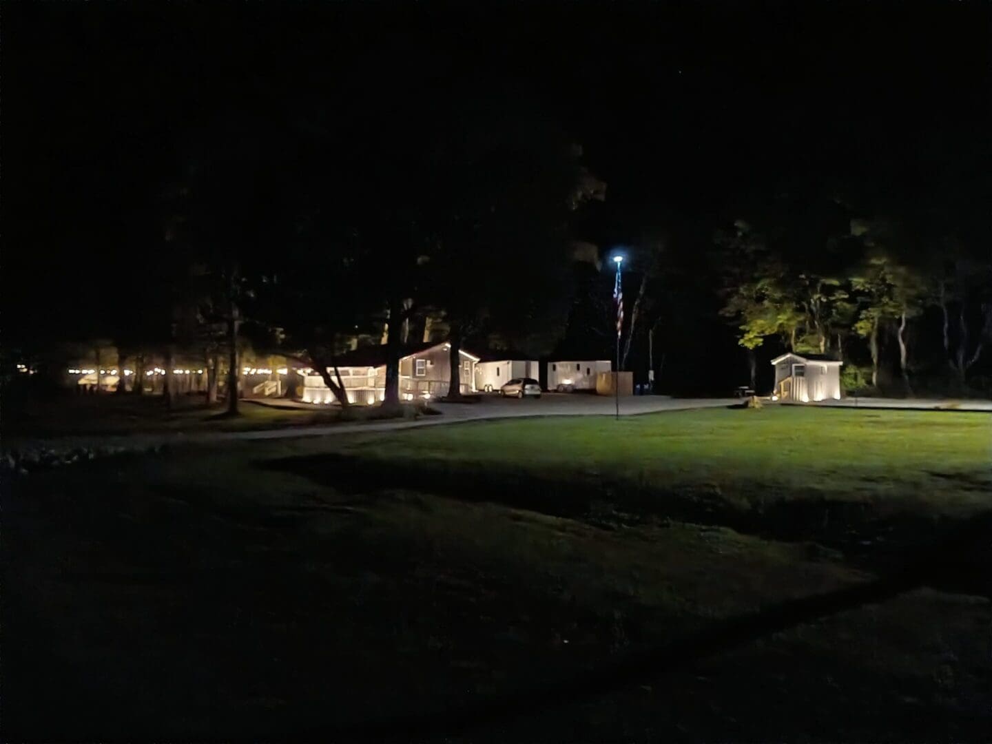 Building illuminated at night with surrounding trees.