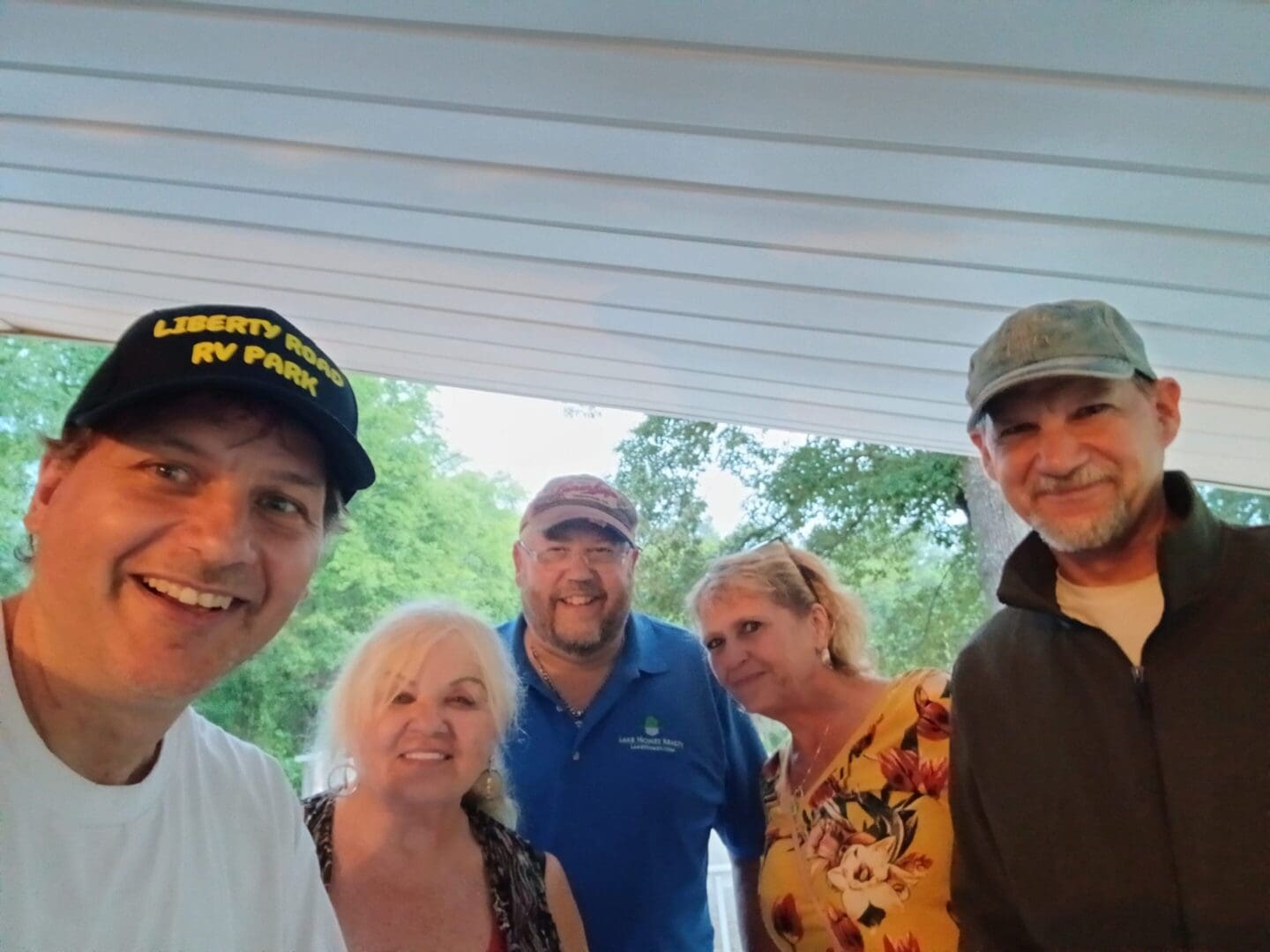 Group of people smiling under a shelter.