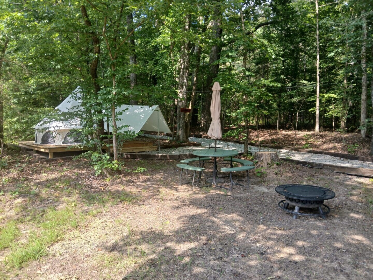 Forest campsite with tent and picnic table.