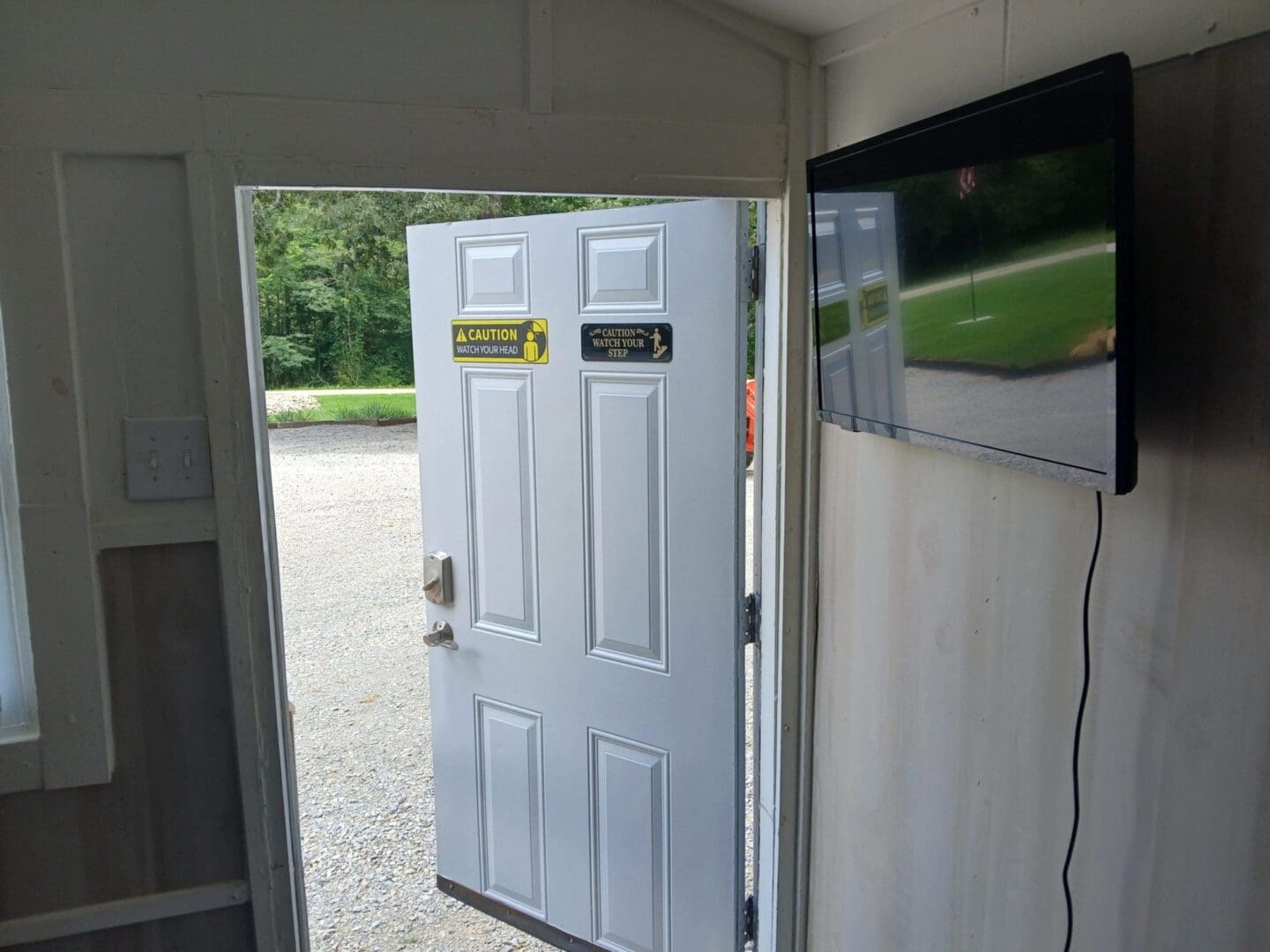 Open door with signs and wall-mounted TV.
