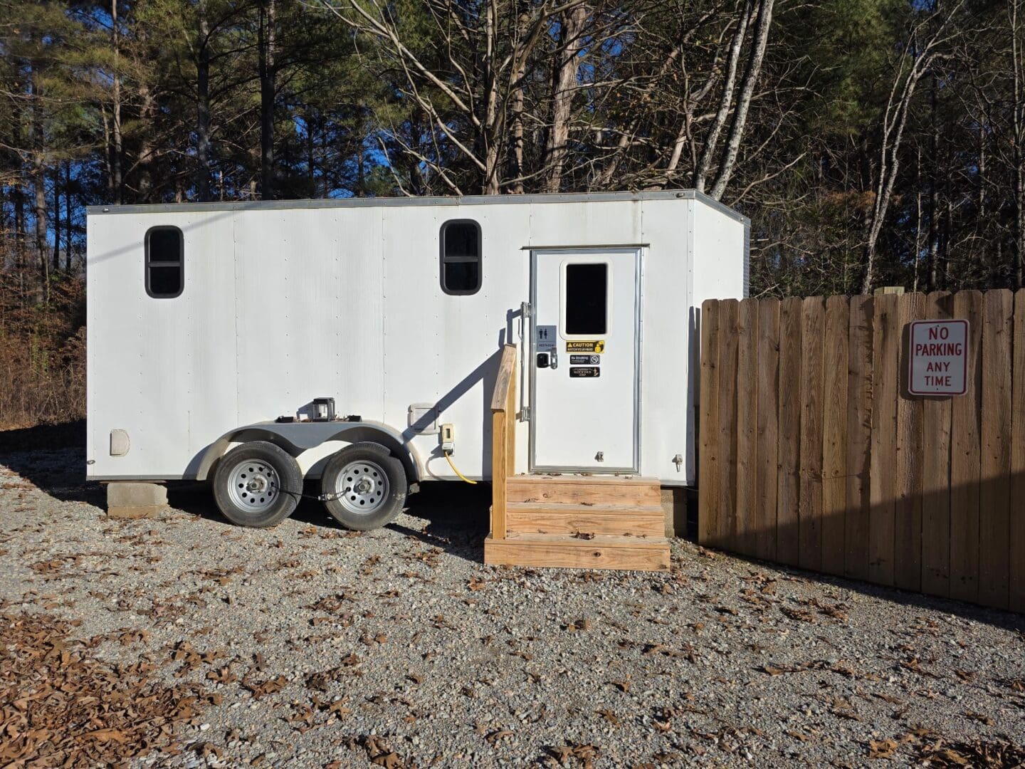 White trailer beside a wooden fence.
