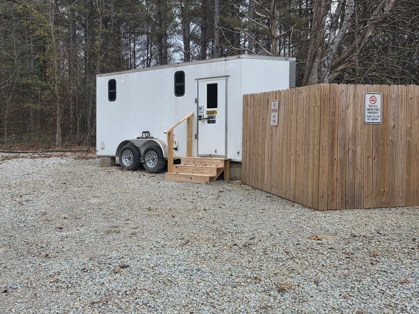 White trailer next to a wooden fence.