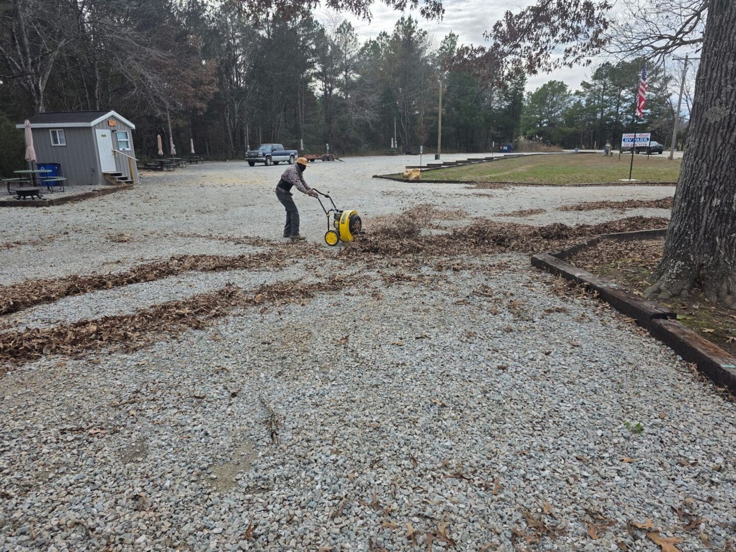 Person using leaf blower on gravel path.