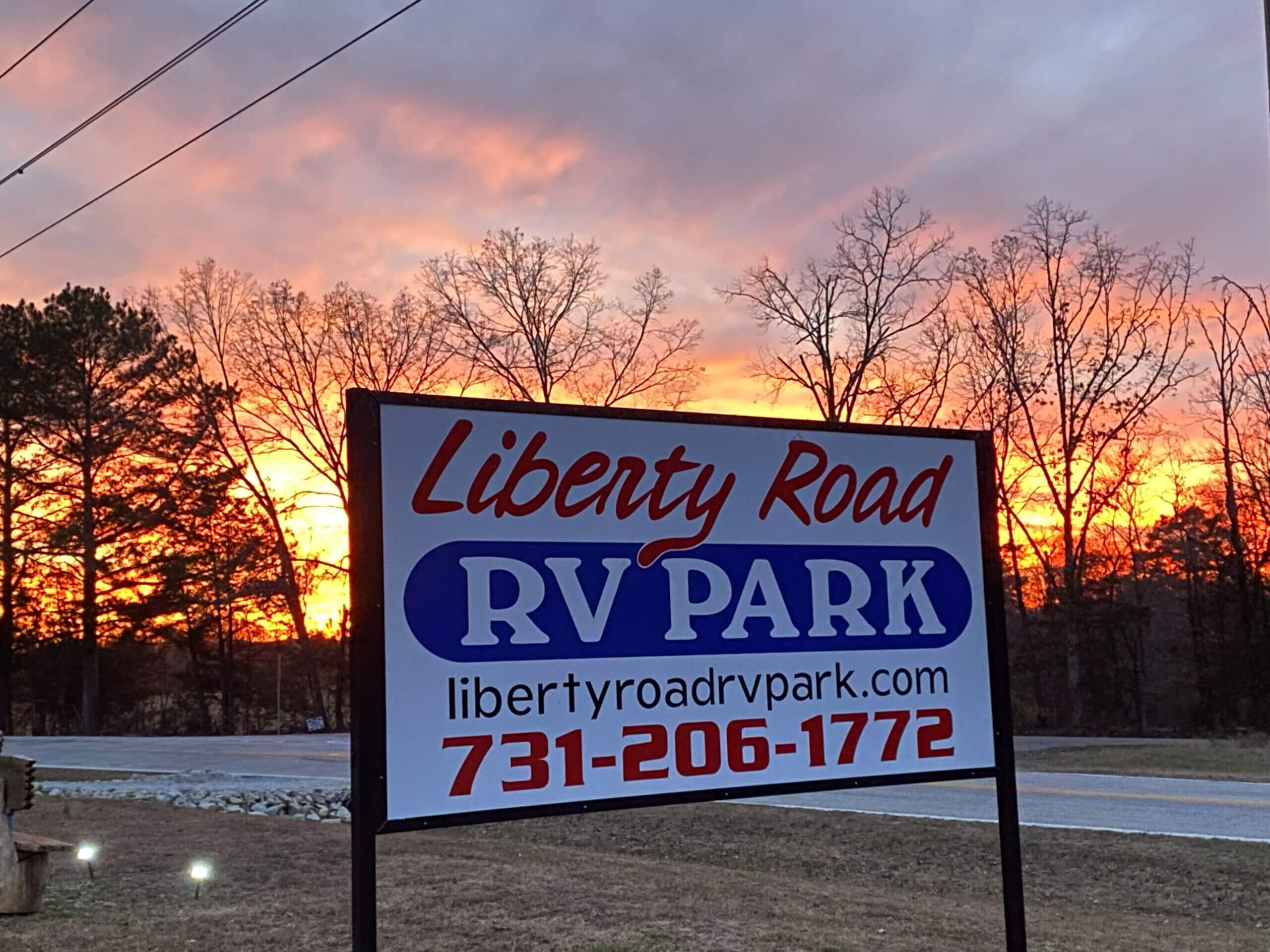 RV park sign with sunset background.