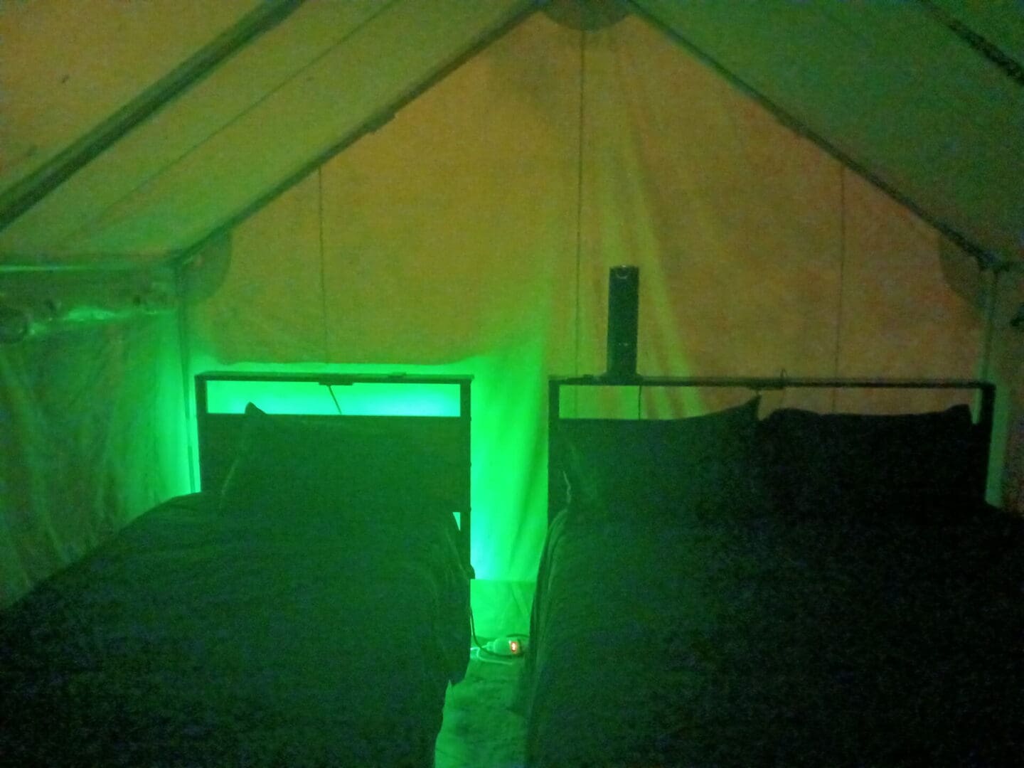 Two beds in tent lit by green light