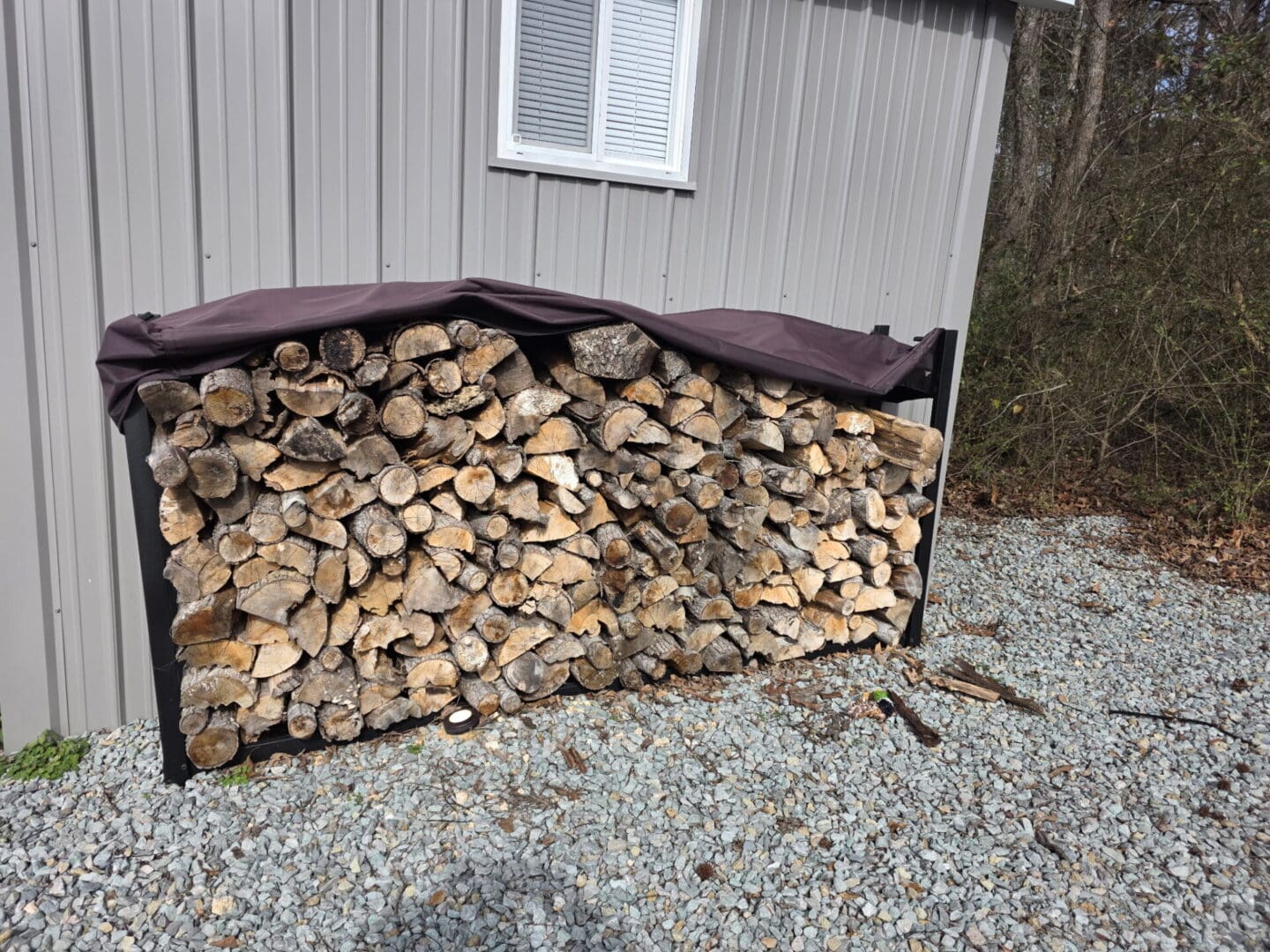 Stacked firewood pile covered by tarp