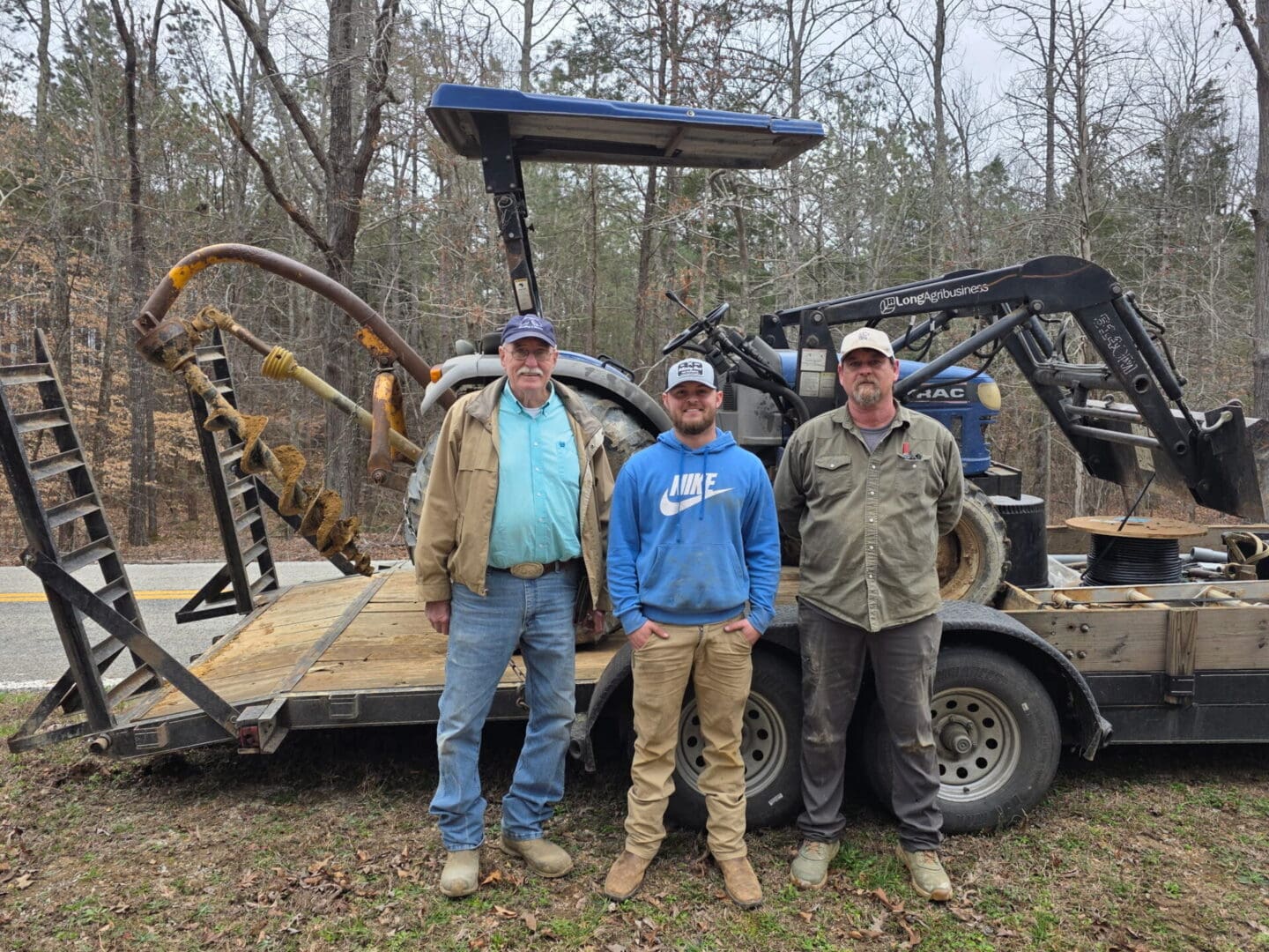 Three men standing by tractor on trailer
