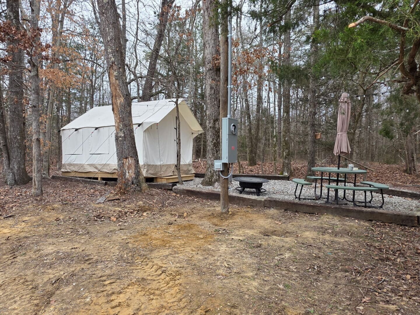 Canvas glamping tent with picnic table and firepit