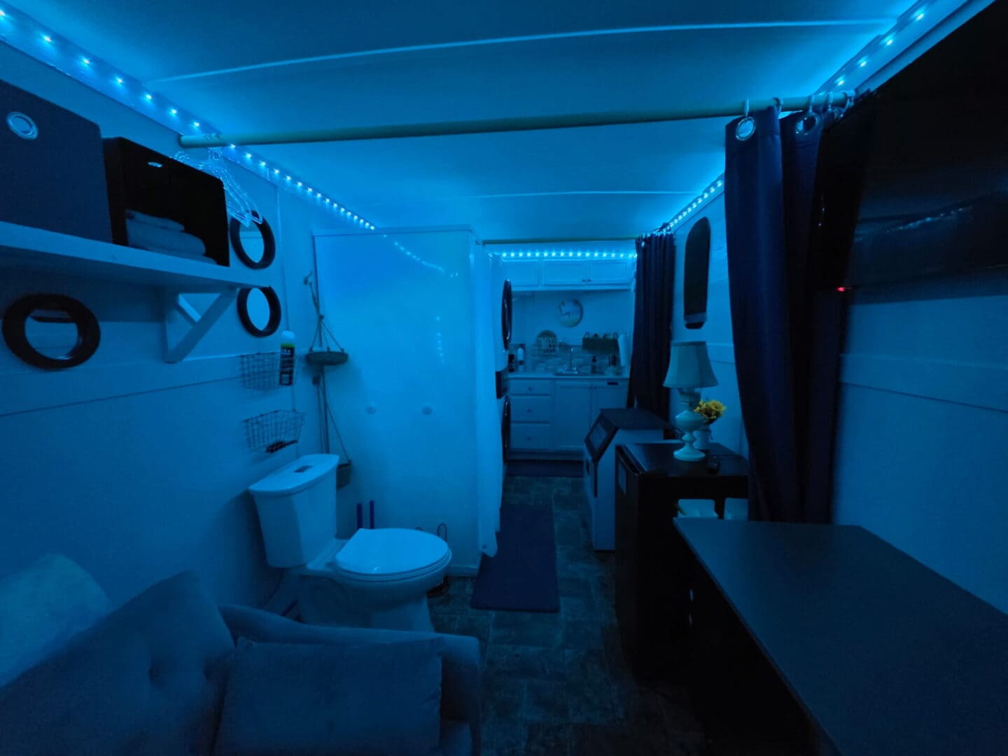 Blue-lit small interior with toilet and kitchenette