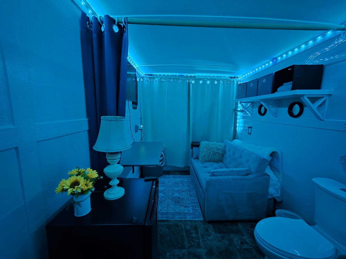 Blue-lit cozy studio with sofa and lamp
