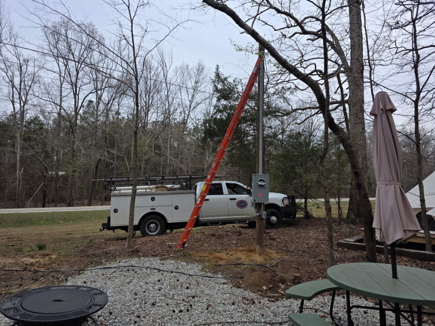 Work truck with ladder leaning on utility pole
