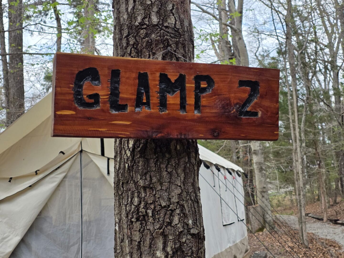 Wooden sign reading "GLAMP 2" on tree