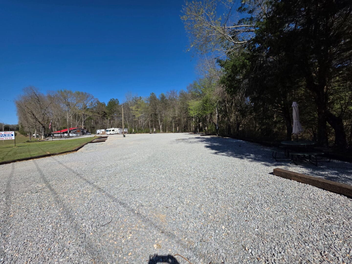 Empty gravel lot with trees and RV