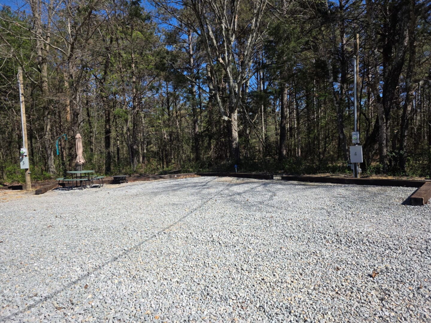 Gravel campsite with picnic table by woods