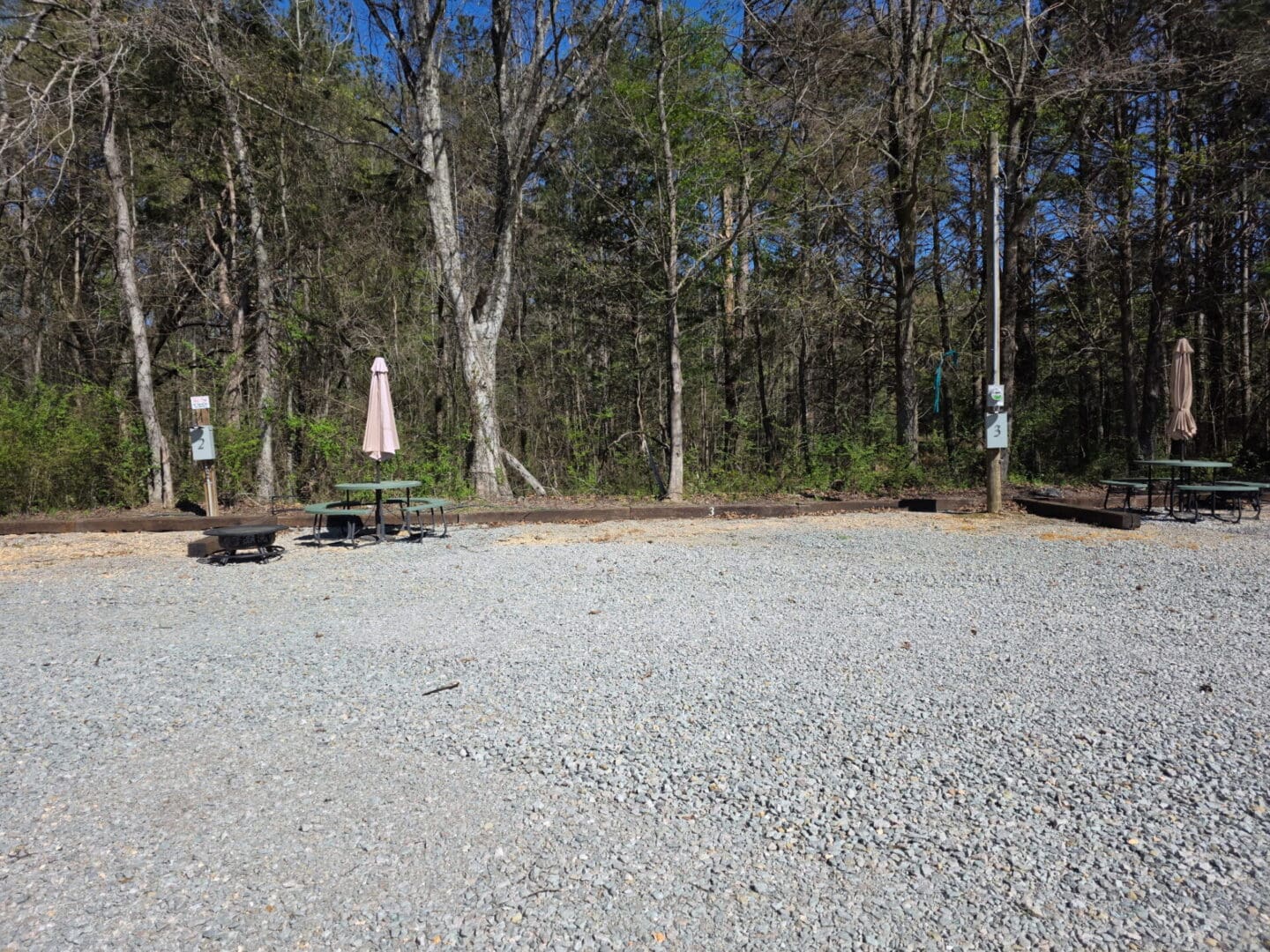 Gravel campsite with picnic tables and umbrellas