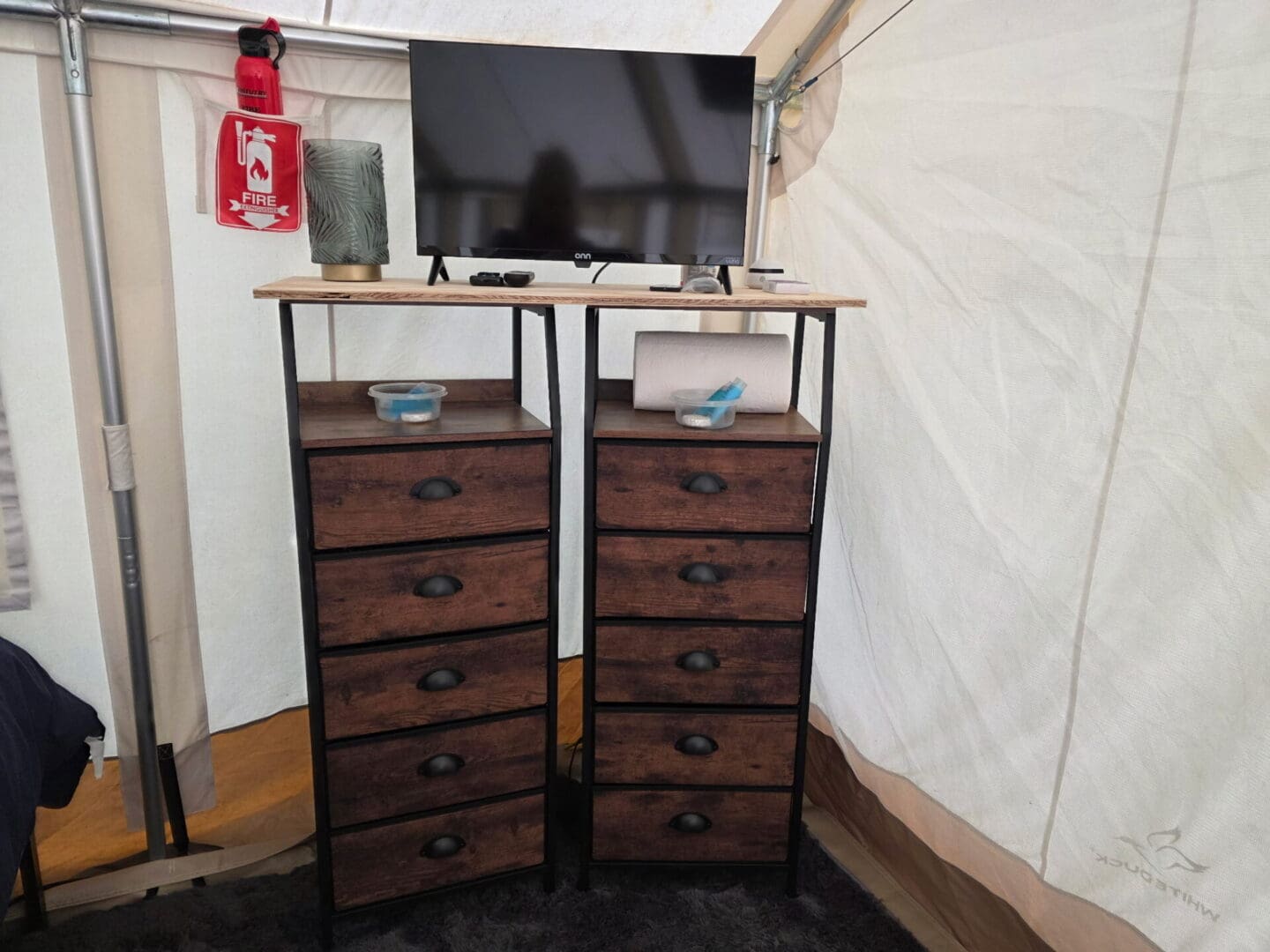 TV on wooden drawers inside tent