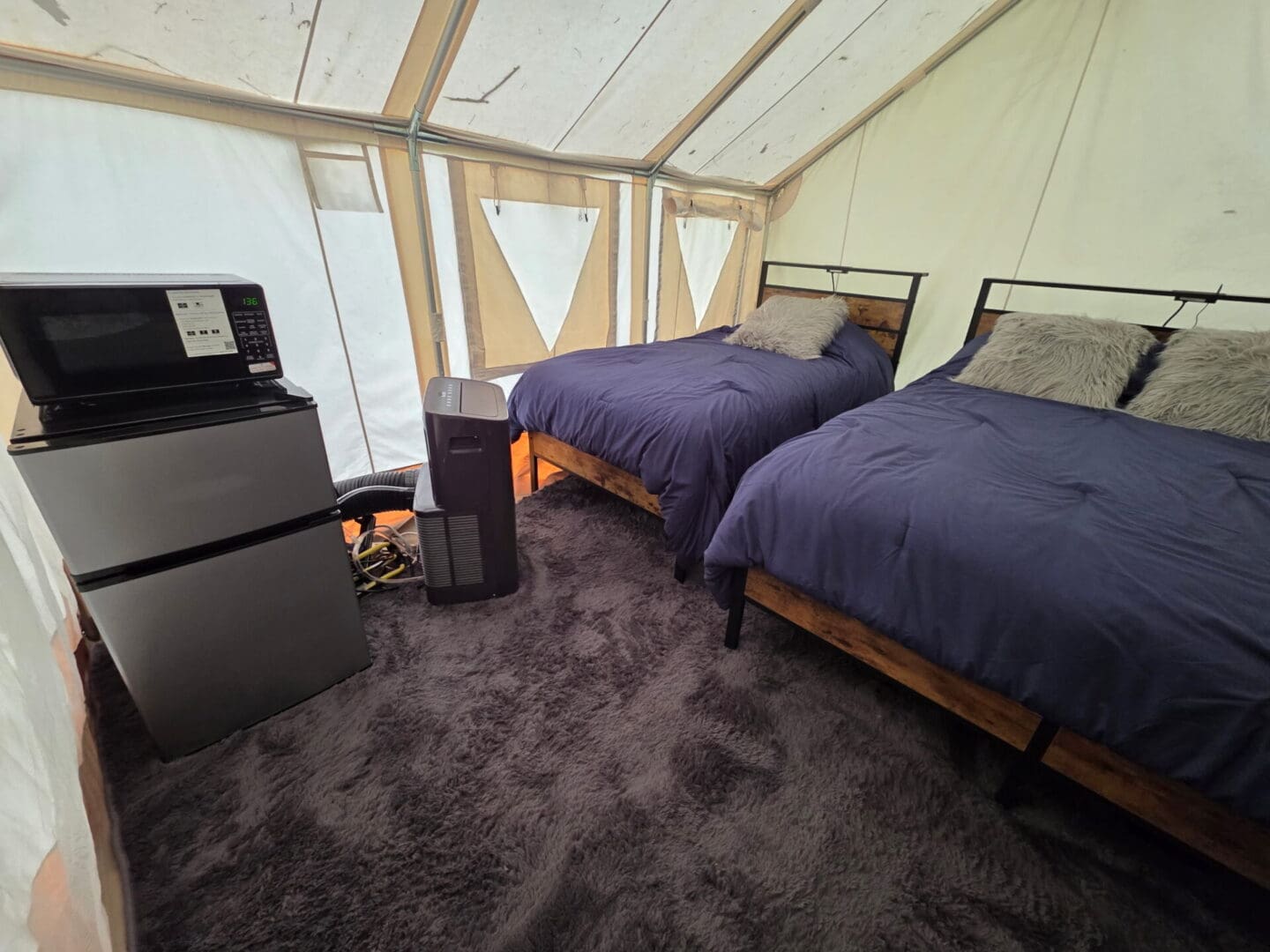 Glamping tent interior with two beds and some appliances
