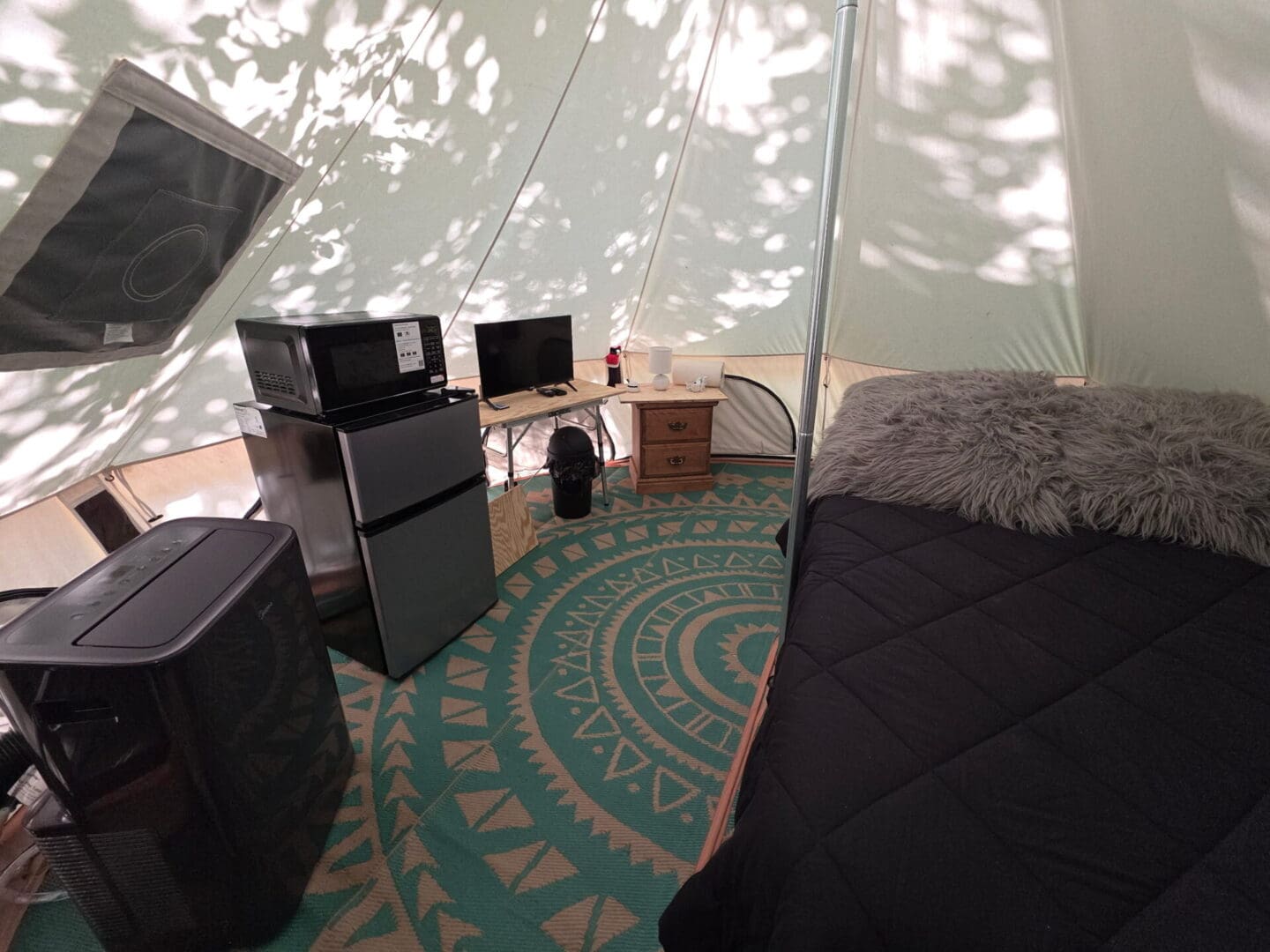 Cozy glamping tent interior with bed and appliances